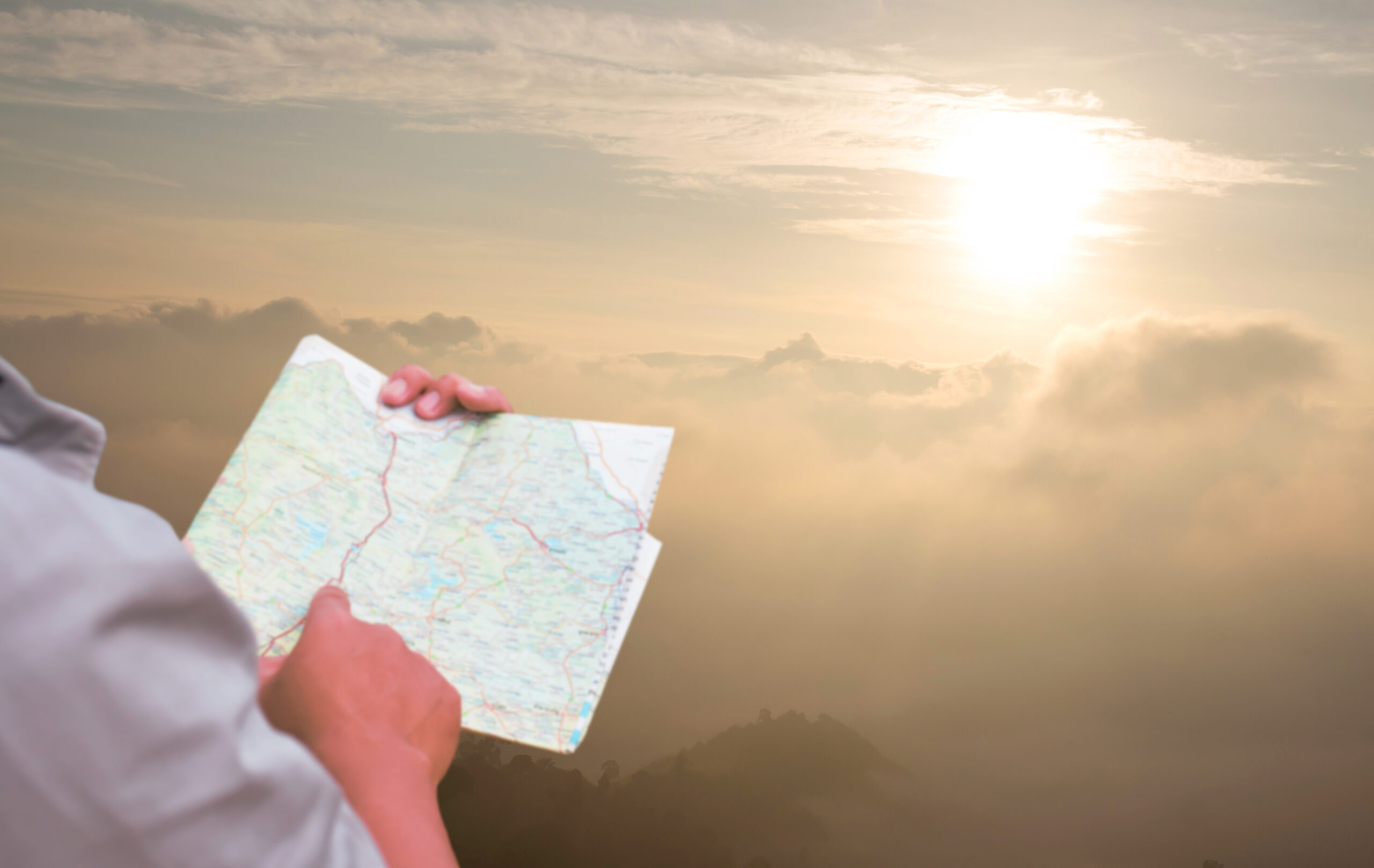 A person is holding and pointing at a road map