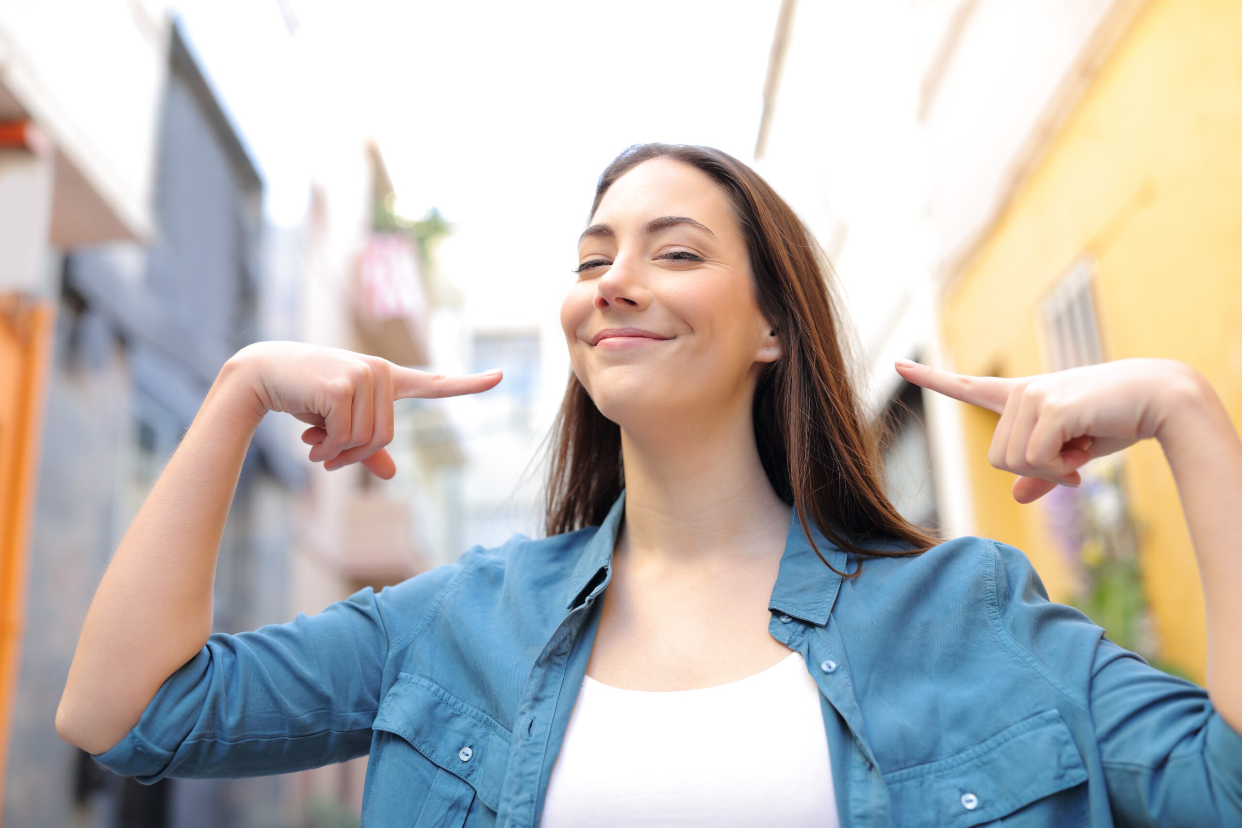 Front view portrait of a proud woman pointing herself in the street
