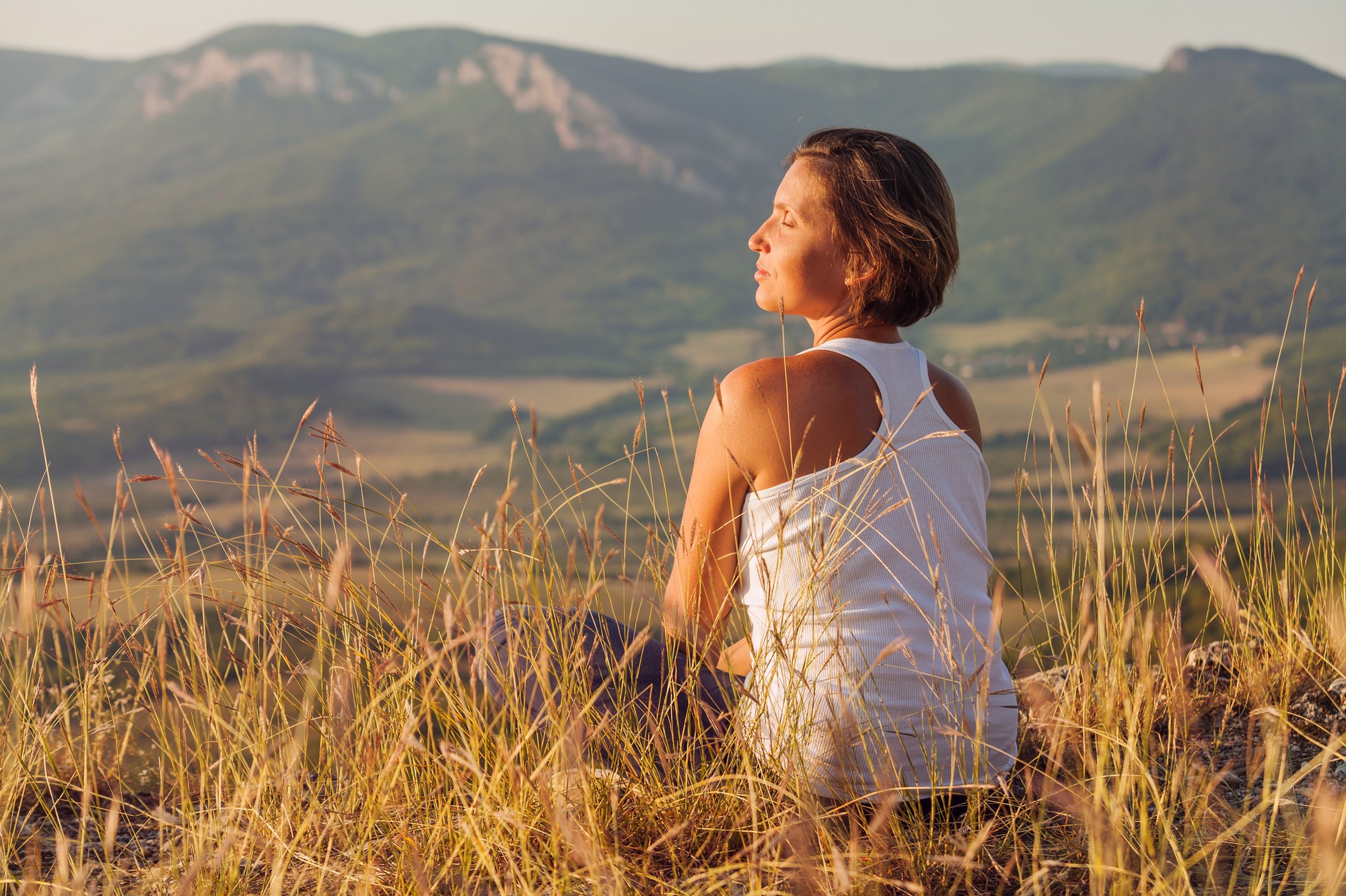 Sitting in meditation pose woman enjoyed with gently shining sunrise